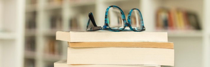 Stack of books with a pair of glasses sitting ontop of the top book